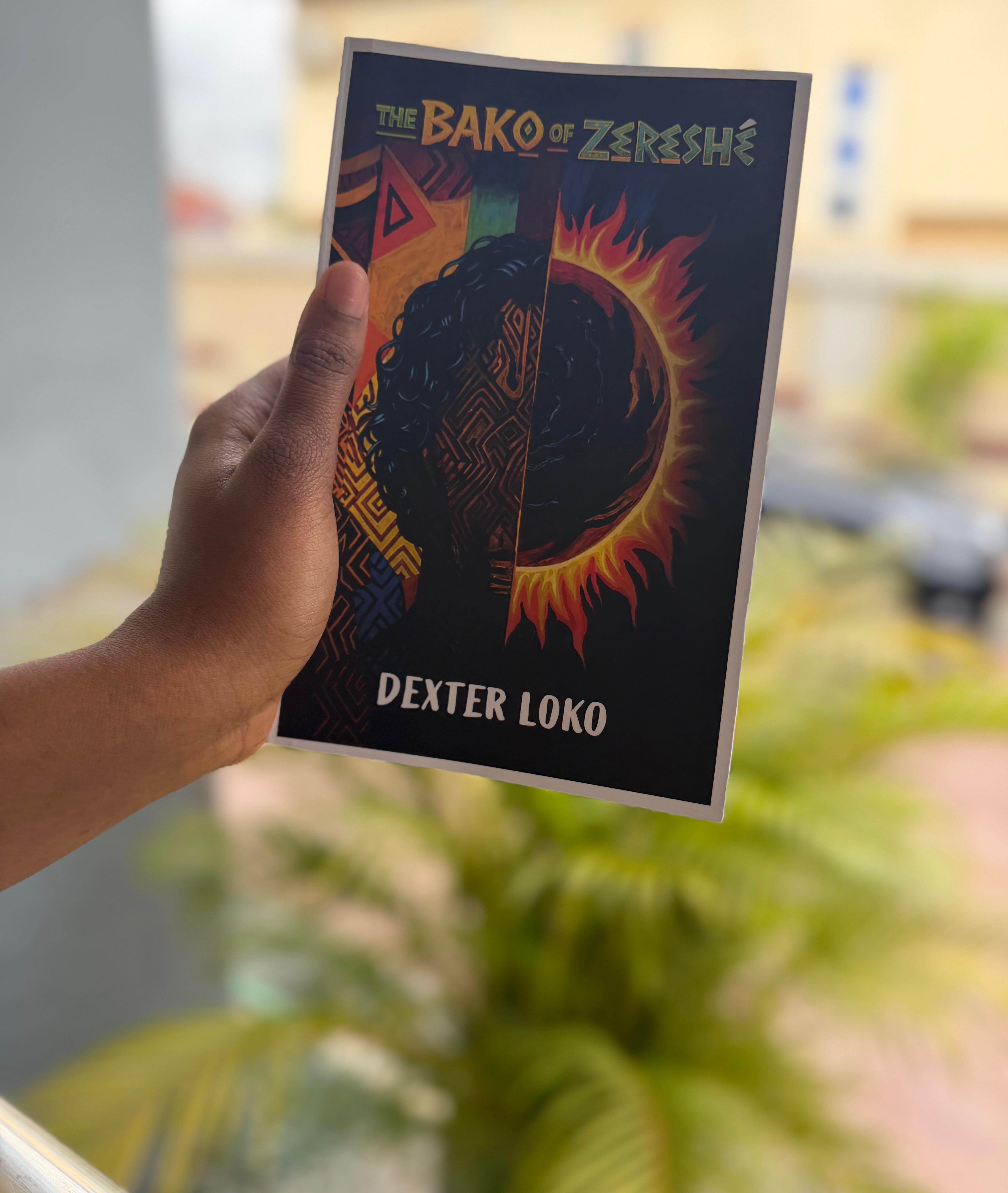 A hand holding a copy of The Bako of Zereshé in front of a bright window.
