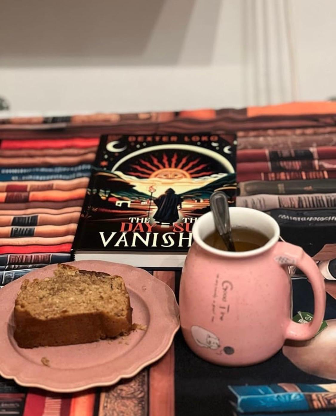 The Day the Sun Vanished beside tea and cake on a book-patterned table.